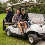 Three men sitting in white golf cart