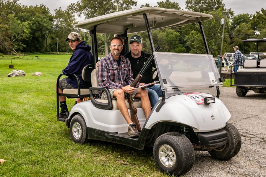 Three men sitting in white golf cart