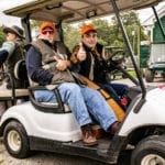 Three hunters with shotguns in golf cart