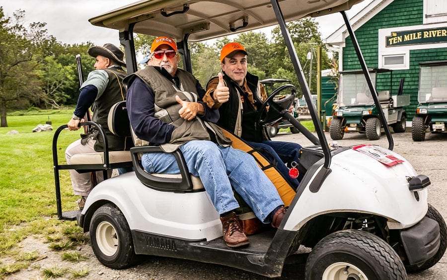 Three hunters with shotguns in golf cart