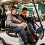 Men riding golf cart with shotguns