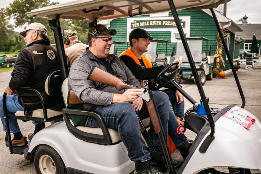 Men riding golf cart with shotguns